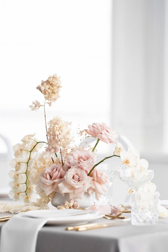 a modern wedding centerpiece of blush roses, white orchids and hydrangeas is a stylish idea for a modern wedding