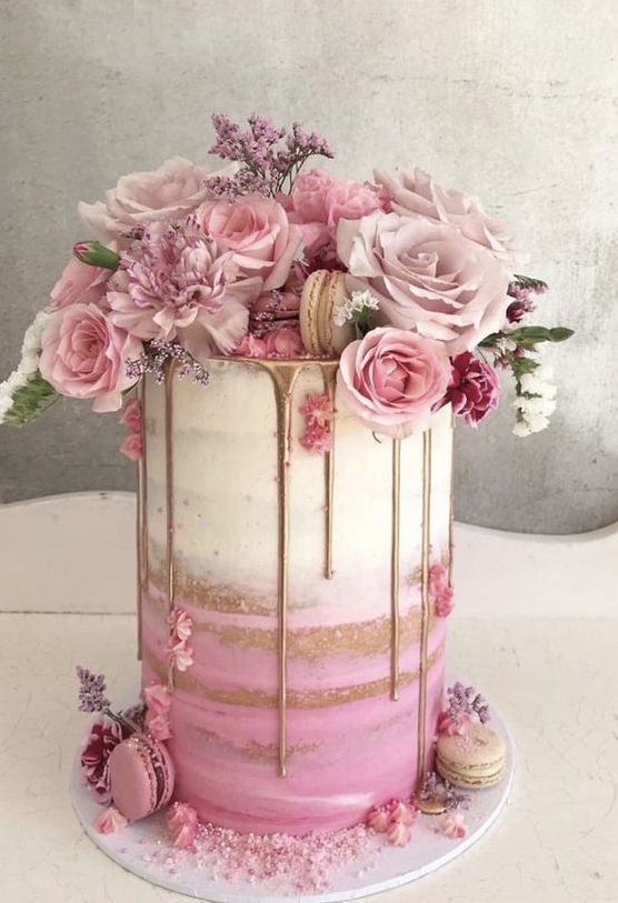 a naked ombre pink wedding cake with gold rip, pink and blush blooms and greenery is adorable for spring