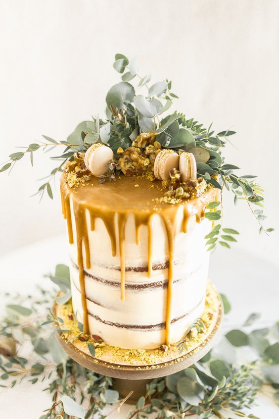 a naked tall wedding cake with caramel drip, neutral macarons, greenery is a lvoely solution for spring or fall