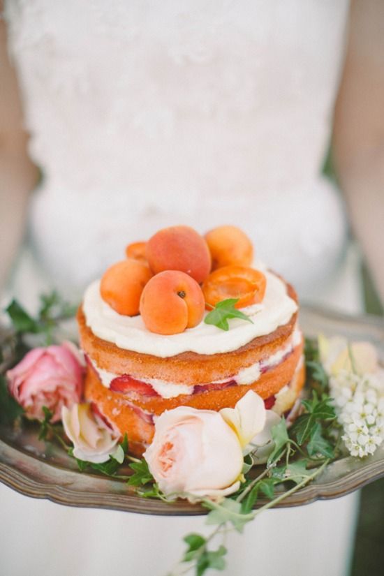 a naked wedding cake with strawberries topped with fresh apricots is a delicious solution for a summer wedding