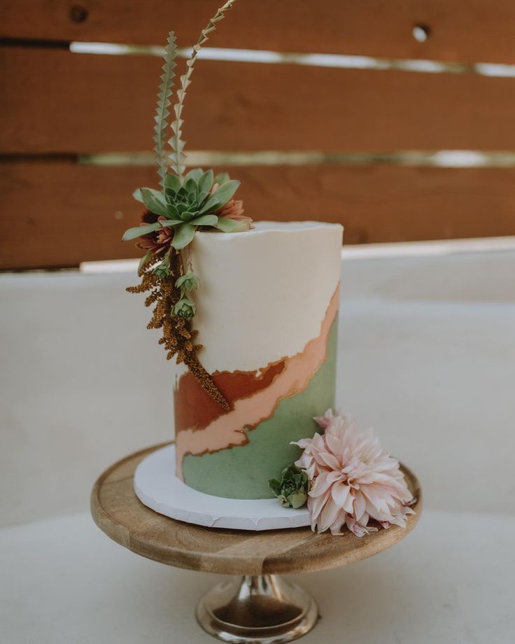 a painted tall wedding cake with greenery, a succulent and a blush bloom for a fall boho wedding