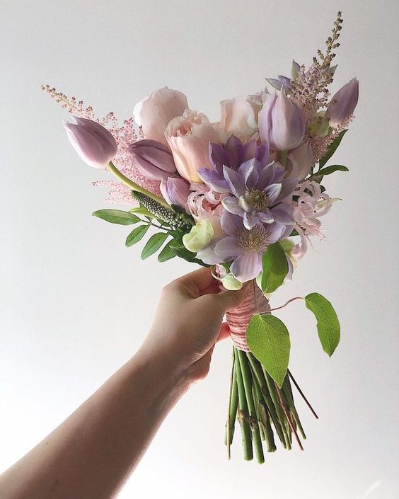 a pastel wedding bouquet of blush and lilac blooms and dahlias, pink astilbe and some foliage is a small but cute arrangement