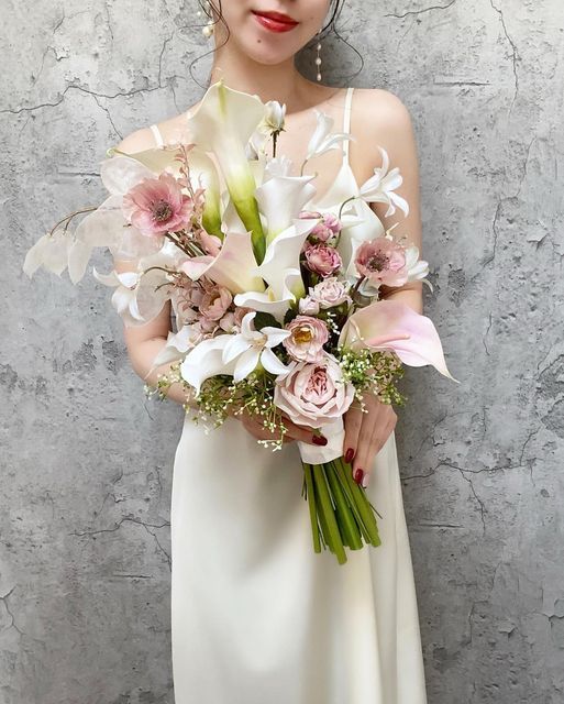 a pastel wedding bouquet of white callas and lilies, blush callas and peony roses plus some lunaria and twigs for the spring