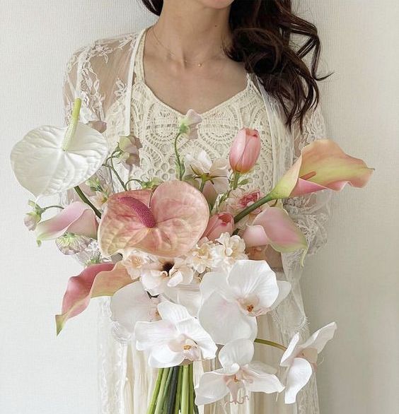 a pastel wedding bouquet of white orchids, pink and white anthuriums, peachy callas and some fillers for the spring