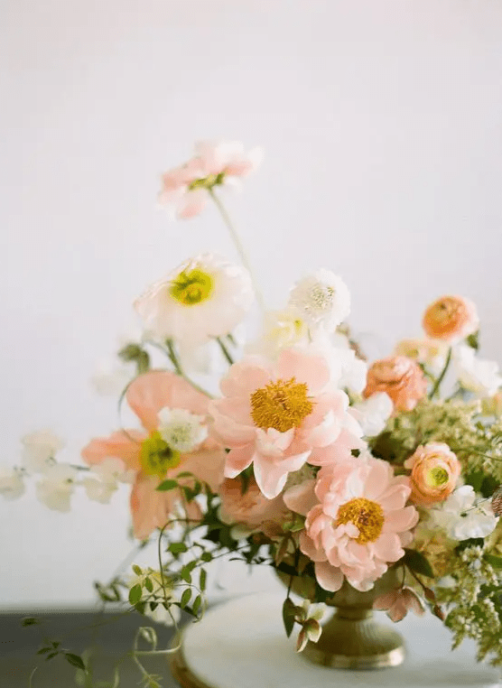 a pastel wedding centerpiece of blush poppies, white blooms and some greenery is a beautiful idea for a spring wedding