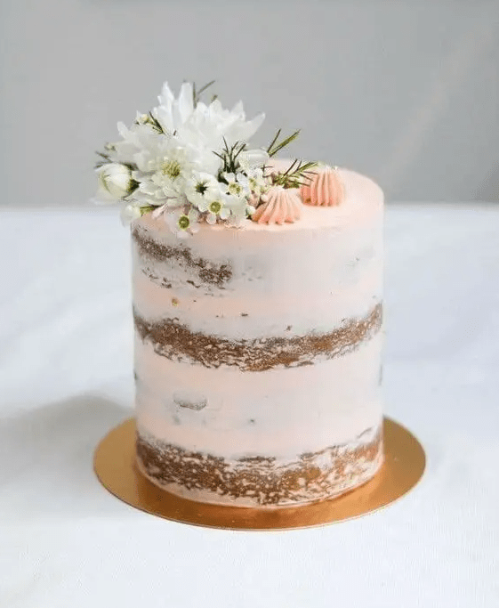 a peachy naked wedding cake topped with white berries and pink meringues is a cool dessert for a spring celebration
