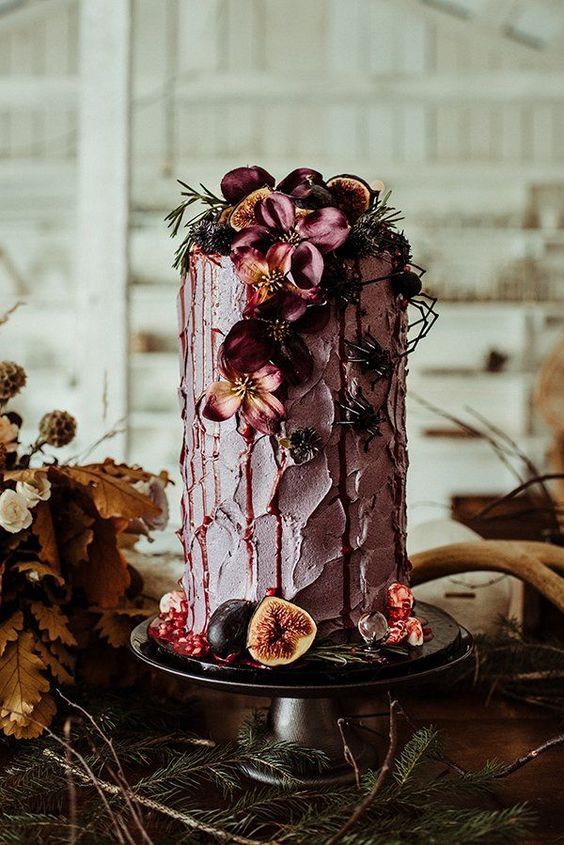 a pink textural wedding cake decorated with dark blooms and greenery, figs and berries for a fall boho wedding