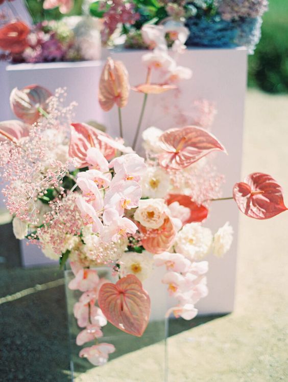 a pink wedding centerpiece of orchids, anthuriums, pink baby's breath and white roses is a chic and cool idea