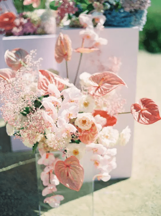 a pink wedding centerpiece of orchids, anthuriums, pink baby’s breath and white roses is a chic and cool idea