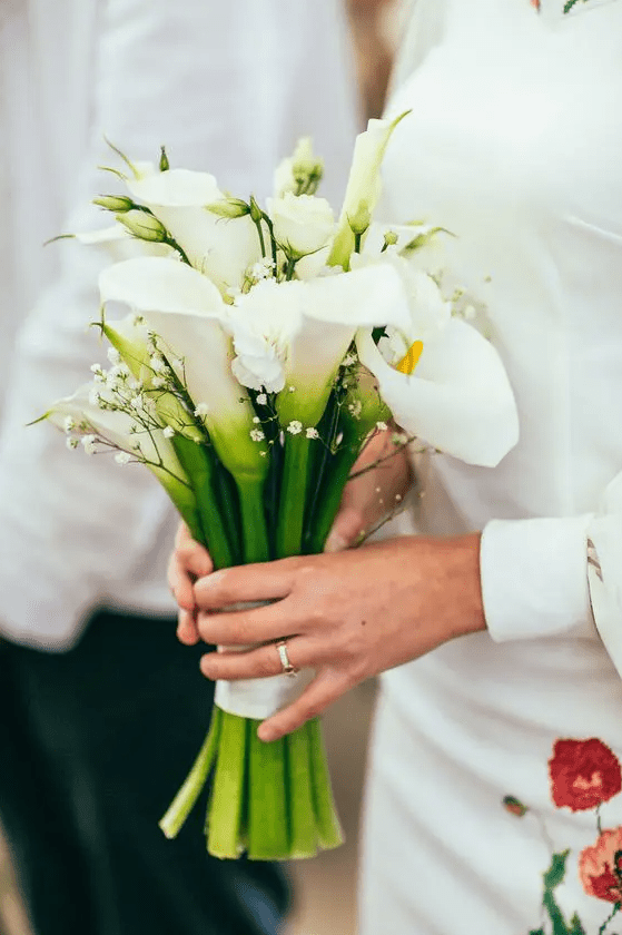 a pretty and chic wedding bouquet of white calla lilies and white baby's breath is a chic and cool idea for a wedding