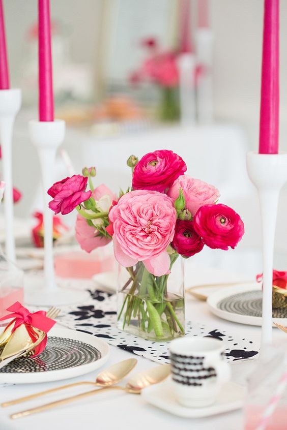 a pretty wedding centerpiece of pink peony roses and fuchsia ranunculus plus hot pink candles around