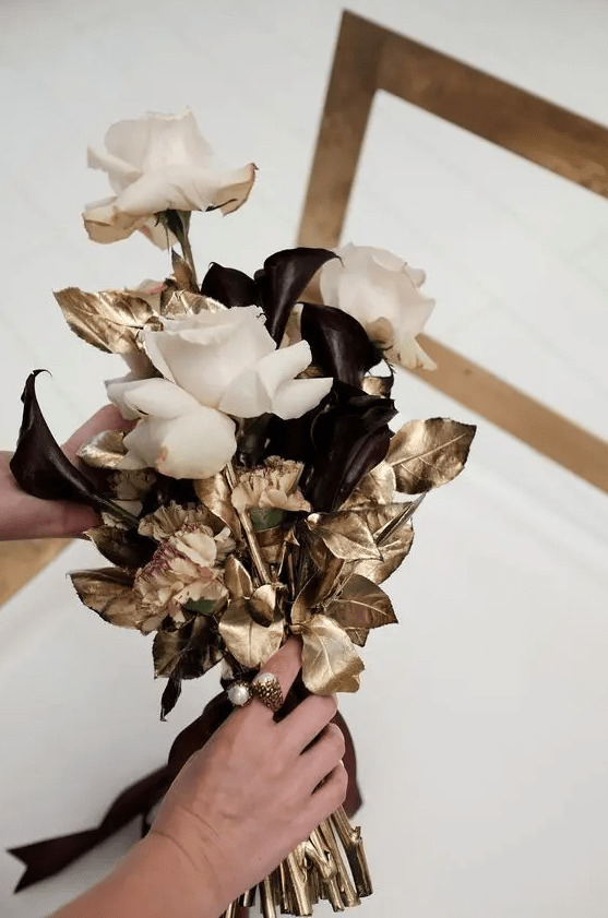 a refined NYE wedding bouquet with blush roses, deep purple callas and gilded leaves is a pretty idea for a glam NYE bride