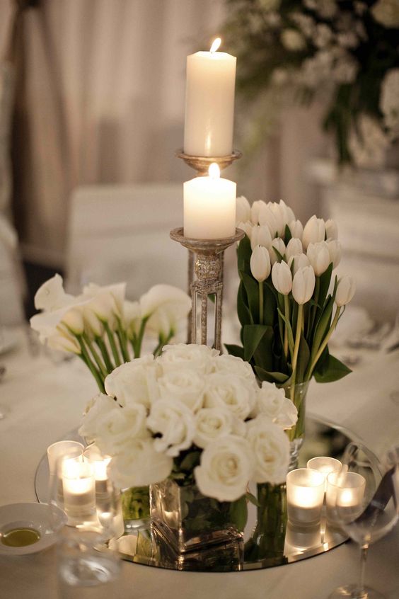 a refined modern wedding centerpiece of white callas, tulips and roses plus candles around is amazing for neutral weddings