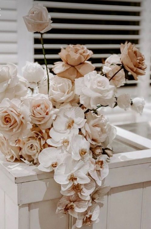 A refined neutral wedding centerpiece of blush and coffee colored roses, white orchids and roses is a cool idea for a modern wedding