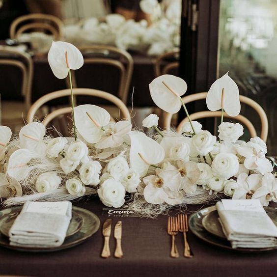 a refined white wedding centerpiece of ranunculus, anthuriums, orchids is amazing for a refined modern wedding