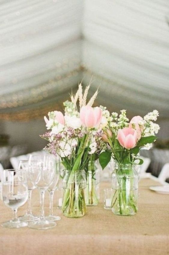 a rustic cluster wedding centerpiece of jars with pink tulips, white and blush fillers and wheat is amazing