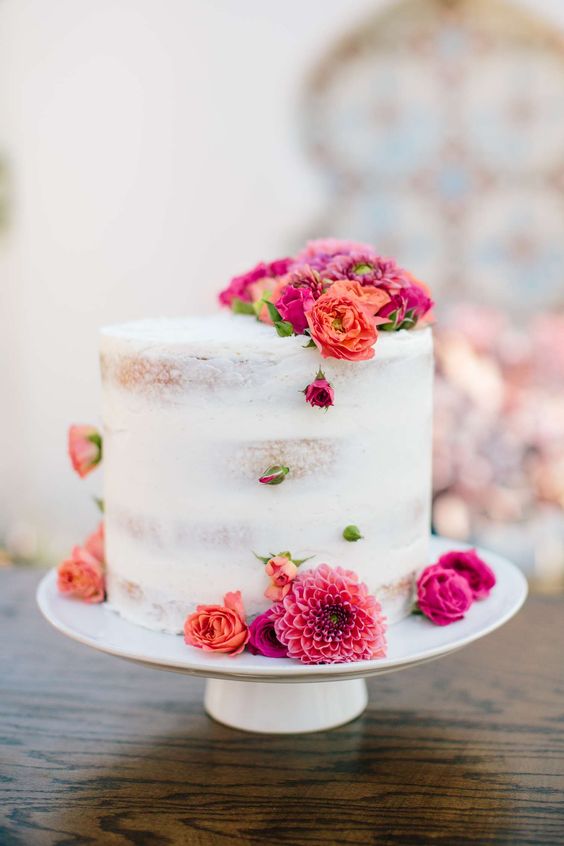 a semi-naked wedding cake topped with fresh blooms is a cool and catchy idea for a summer wedding