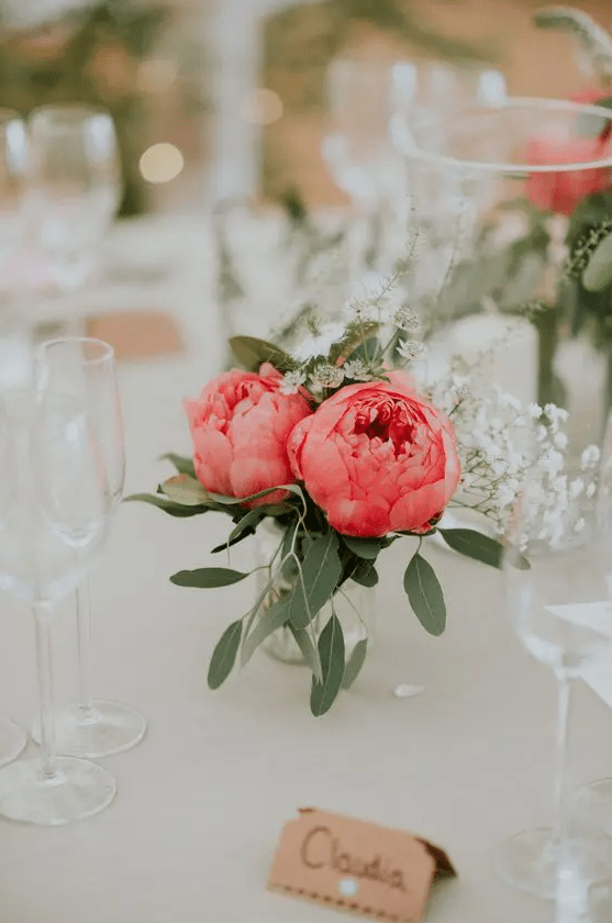 a simple wedding centerpiece of bold pink peonies and white wildflwoers and greenery can be easily composed by you yourself