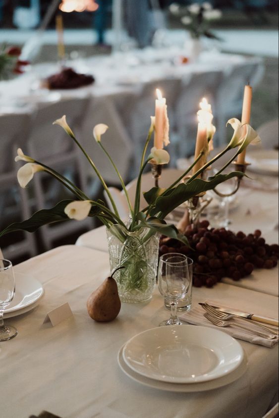 a simple wedding centerpiece of white callas, a pear and grapes right on the table are a lovely combo for a modern wedding