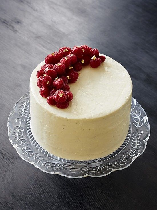 a sleek and simple ivory wedding cake topped with fresh raspberries and gold foil is adorable for many weddings