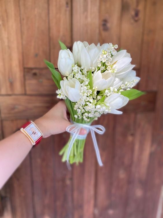 a small and catchy spring wedding bouquet of white tulips and lily of the valley is a super cool and lovely solution