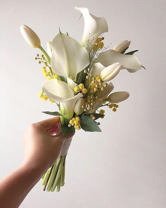 a small and cool spring wedding bouquet of white callas, tulips, mimosa and some greenery is a lovely idea