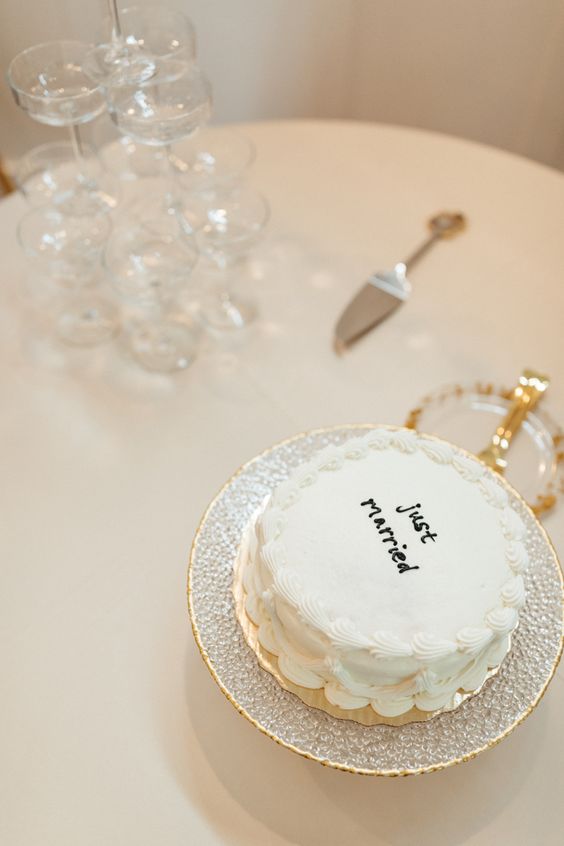 a small and simple white wedding cake with black chocolate calligraphy is all you need for a trendy wedding