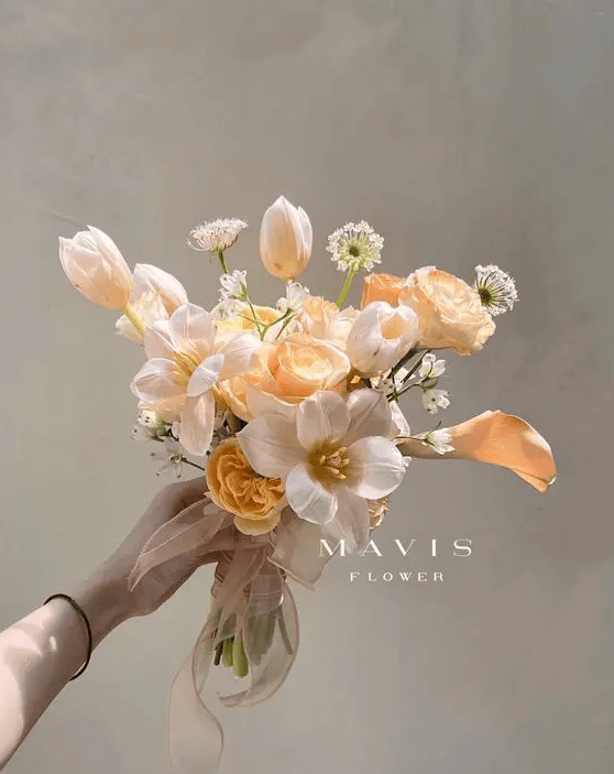 a small peachy wedding bouquet of peachy and blush tulips, peachy peony roses and callas and some fillers for spring or summer