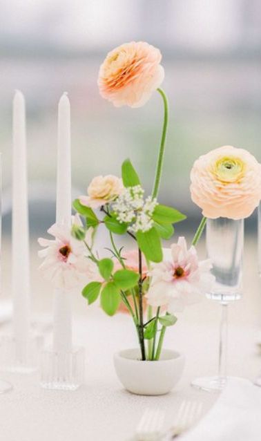 a small spring wedding centerpiece of orange ranunculus, pink blooms and greenery is a cool idea for a modern wedding