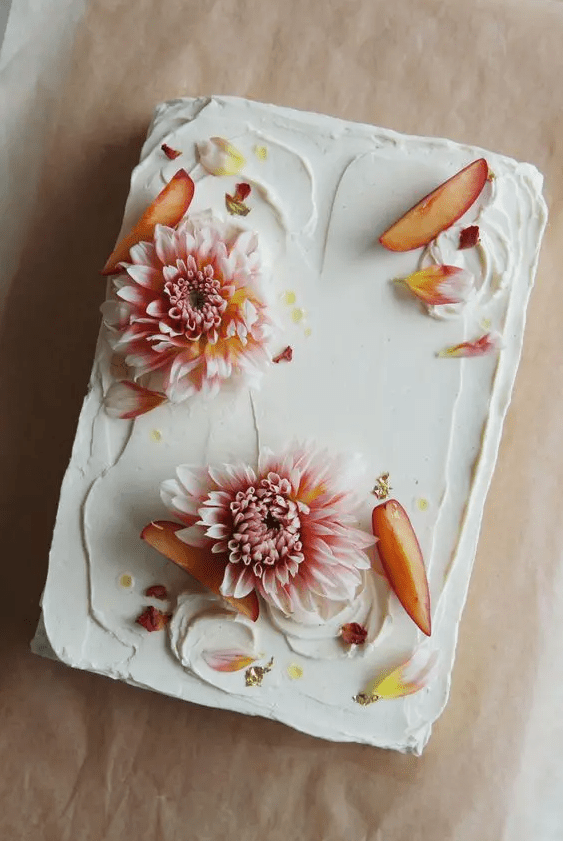 a small white sheet wedding cake topped with fresh blooms, petals and peaches is a cool idea for a small summer wedding
