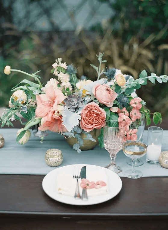 a soft centerpiece with pink peonies, ranunculus, succulents and textural greenery is a great idea for the summer