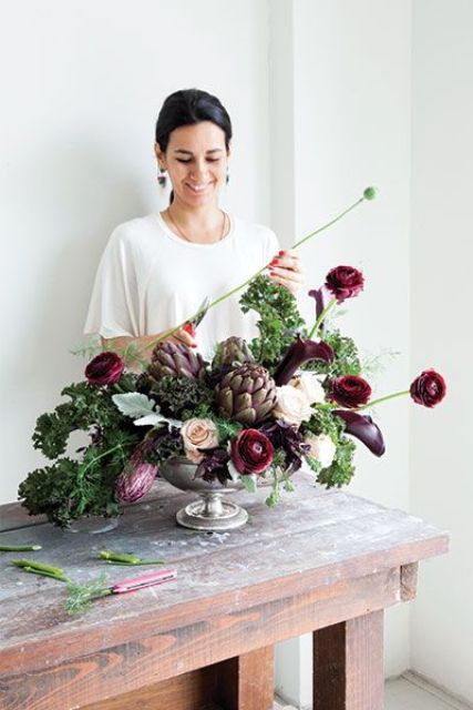 a sophisticated fall wedding centepiece of deep purple callas, ranunculus, greenery, artichokes is amazing, chic and moody