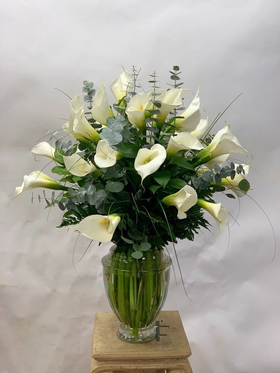 a sophisticated modern wedding centerpiece of white callas, greenery and twigs is a chic idea fro a modern neutral wedding
