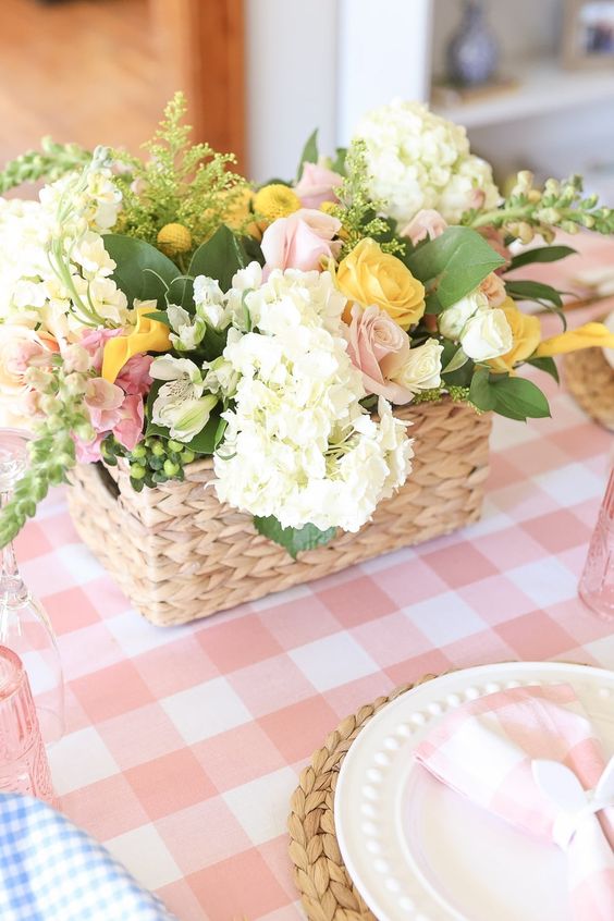a spring basket wedding centerpiece of white hydrangeas, pink and yellow roses and billy balls and some greenery