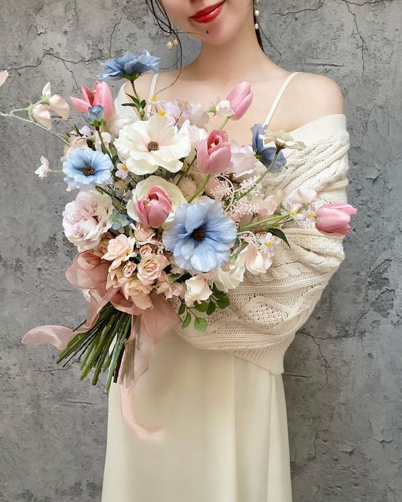 a spring wedding bouquet of pink tulips, blush roses and neutral and blue blooms is a lovely arrangement in muted colors