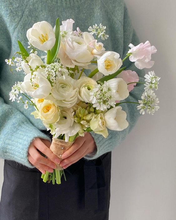 a spring wedding bouquet of white tulips, ranunculus, blush sweet peas and fillers is a chic and lovely idea