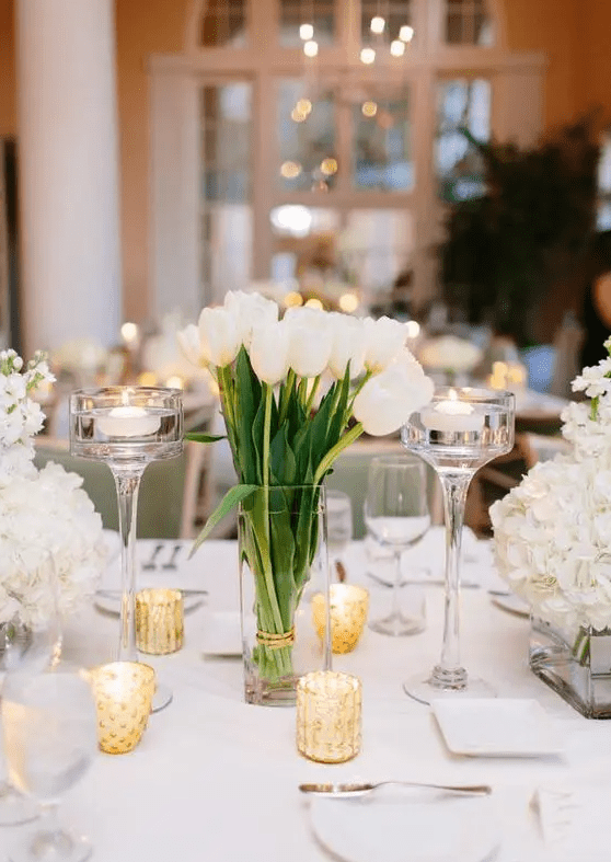 a stylish cluster wedding centerpiece of white hydrangeas, tulips and candles around is an elegant and chic idea to rock