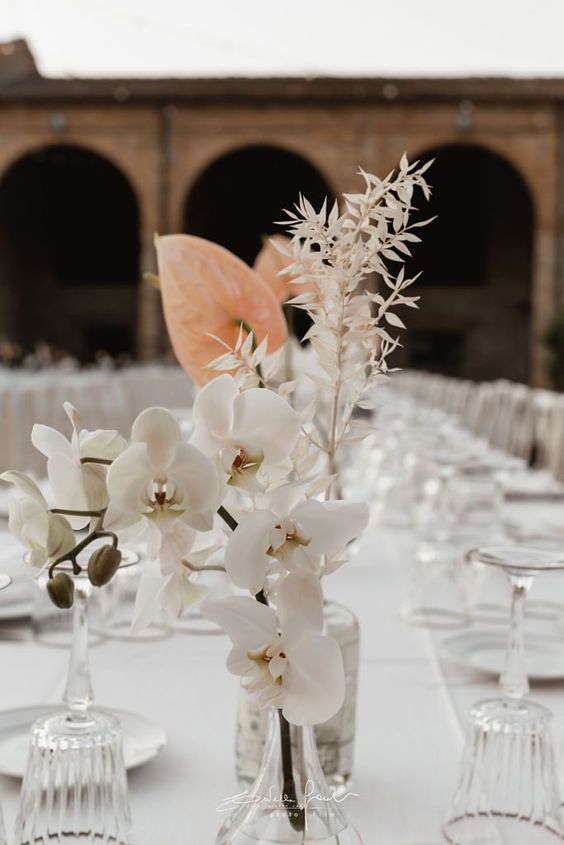 a stylish modern wedding centerpiece of white orchids, blush anthuriums and dried branches is amazing