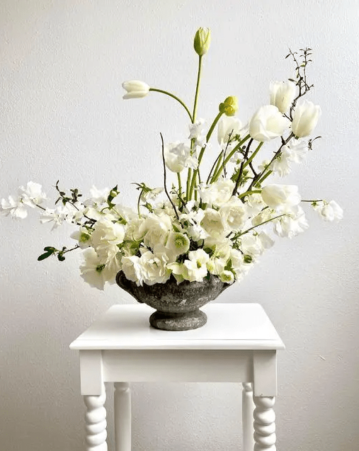 a stylish white wedding centerpiece of tulips, orchids and poppies styled as ikeabana is adorable