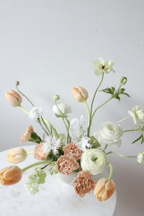 a subtle wedding centerpiece of white ranunculus, peachy tulips and some neutral blooms is amazing for a fine art wedding