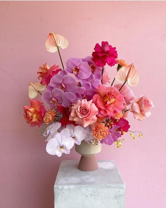 a super bold wedding centerpiece of pink, white orchids, pink, blush roses and anthuriums is a cool and catchy idea