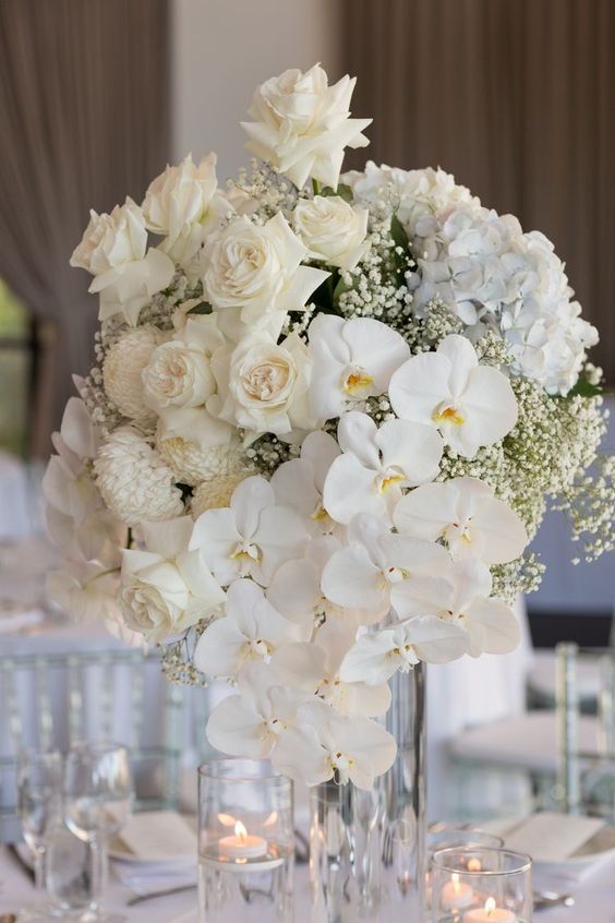 a super lush tall wedding centerpiece of roses, hydrangeas, orchids, mums and baby's breath is amazing