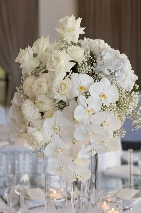 a super lush tall wedding centerpiece of roses, hydrangeas, orchids, mums and baby's breath is amazing
