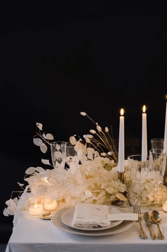a super lush wedding centerpiece of lunaria and bunny tails and small and tall candles is a lovely and chic idea for a neutral wedding