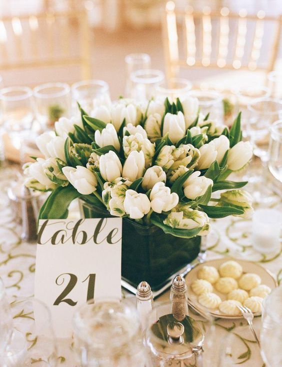 a super lush white tulip centerpiece in a dark vase for a contrast is a cool idea for a neutral wedding