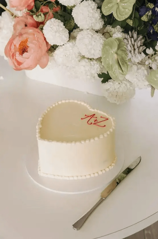 a super simple white heart-shaped wedding cake with monograms is always a good idea for a casual wedding