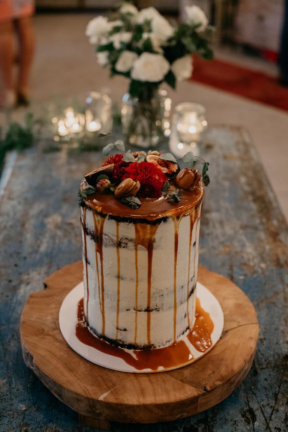 a tall naked wedding cake with caramel drip, macarons, blooms, nuts and leaves is ideal for the fall
