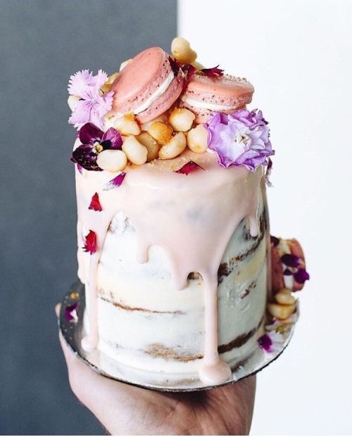 a tall naked wedding cake with pink drip, pink macarons, hot pink blooms and nuts is ideal for spring