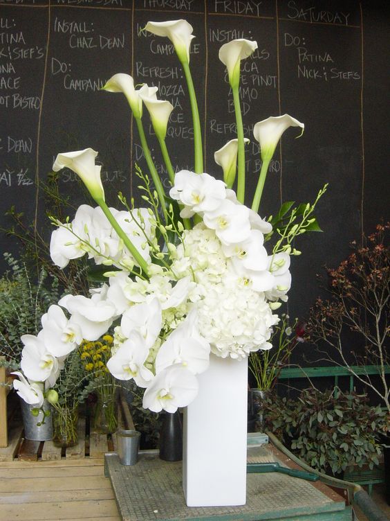 a tall wedding centerpiece of white hydrangeas, callas and orchids is a stylish and catchy idea for a modern neutral wedding