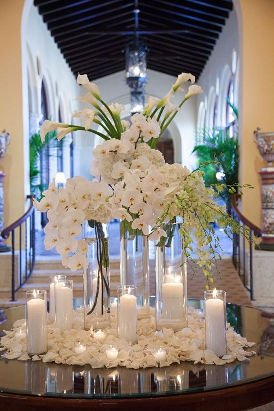 a tall wedding centerpiece of white orchids, callas and hydrangeas surrounded with candles is amazing for a formal wedding